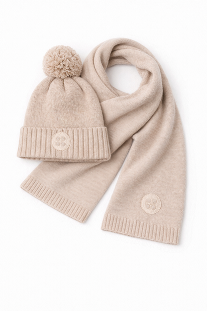 Beige knit hat with pom-pom and scarf on a white background
